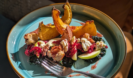 Wedges of roast squash next to a salad of cavalo nero, soft fresh cheese, sliced apple, croutons and Sauerbeet which is fermented beetroot and red cabbage.
